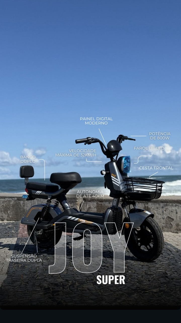 E-bike Joy Super cinza estacionada no calçadão de Copacabana com o mar ao fundo